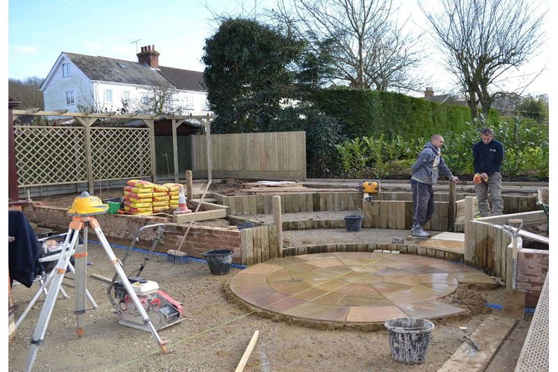 Building the central paving feature with trellis and fencing in the background