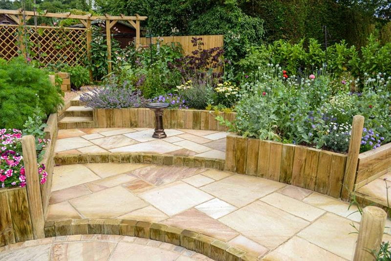 garden with steps from landscape timbers and single wooden pergola